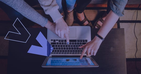 Three people huddled around a small laptop to establish an ecommerce website redesign strategy.